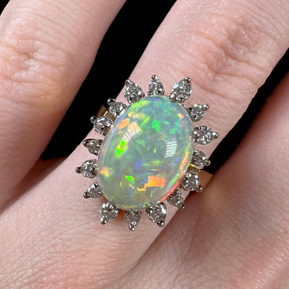 A macro close-up of a 4.30ct Lightning Ridge fire opal engagement ring worn on the engagement finger.  The opal displays a mix of red and green fire.