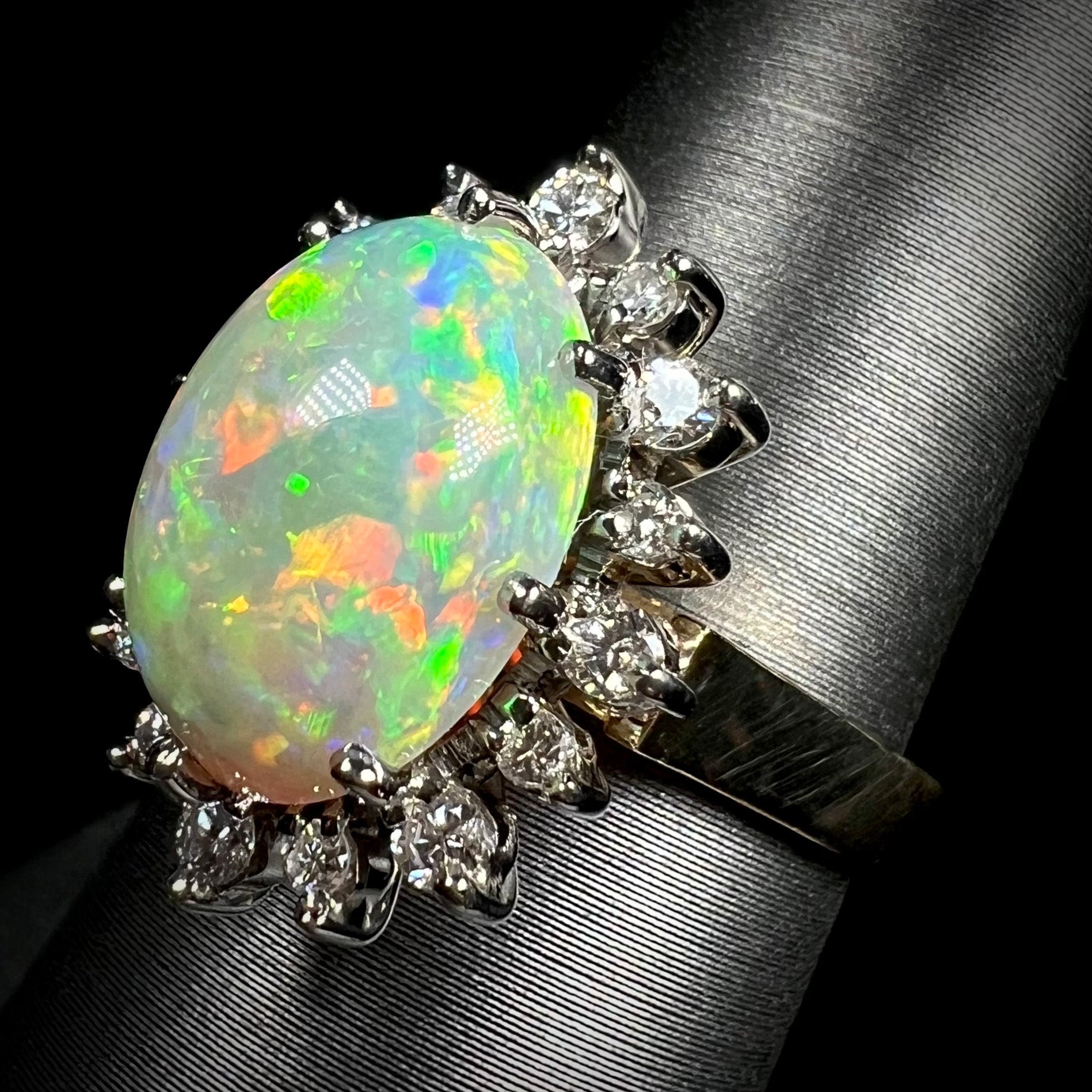 A 4.30ct Lightning Ridge fire opal engagement ring in 18k gold, shown at an angle.  The opal's red and green fire is visible, surrounded by a diamond halo.