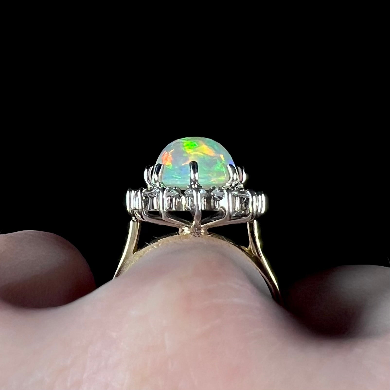 A close-up profile view of a 4.30ct Lightning Ridge fire opal engagement ring worn on the engagement finger.  The white gold diamond halo and opal's depth are visible.