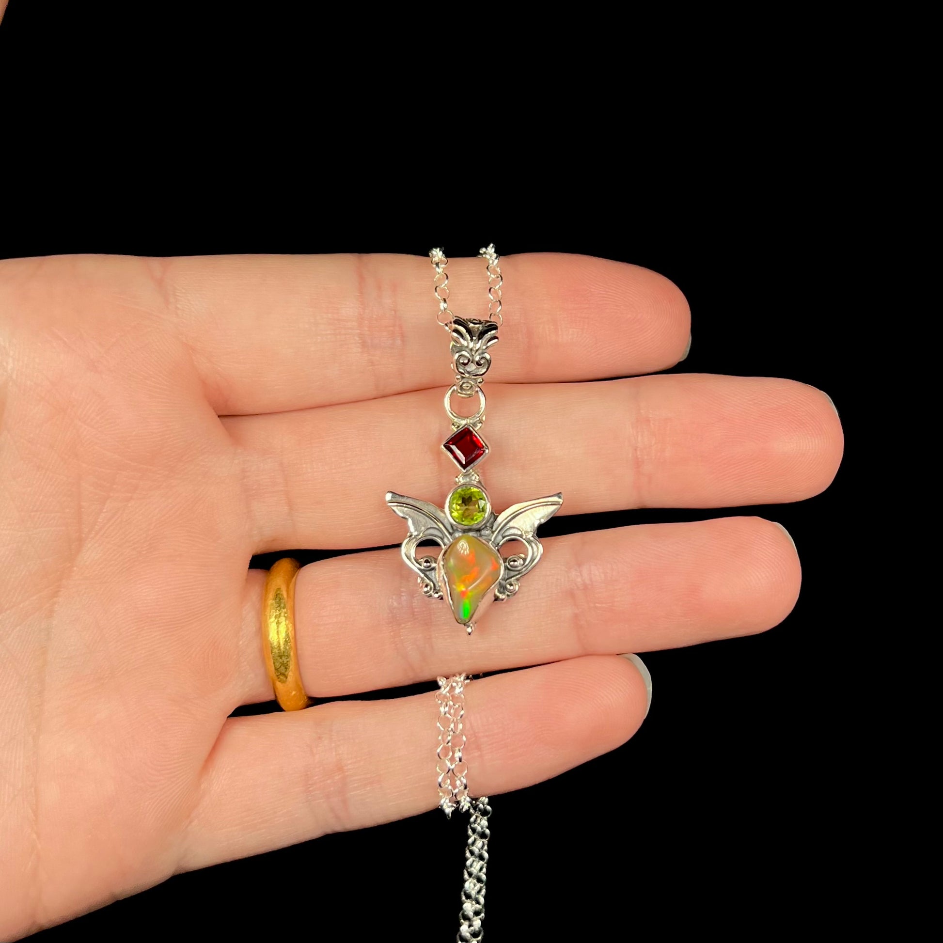 A sterling silver angel pendant set with an Ethiopian fire opal, peridot, and garnet.
