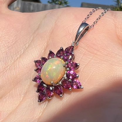 Sunlit angled close-up of a sterling silver Ethiopian opal and rhodolite garnet spray necklace.