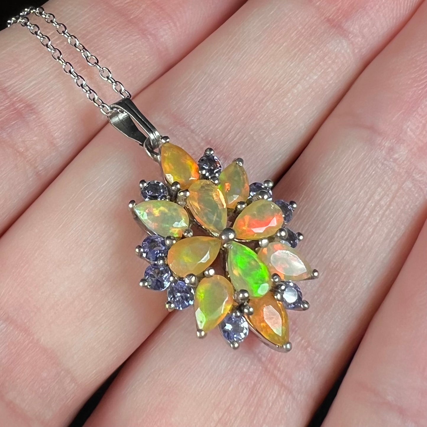 An Ethiopian fire opal pendant shown close-up in a hand, held at an ange.