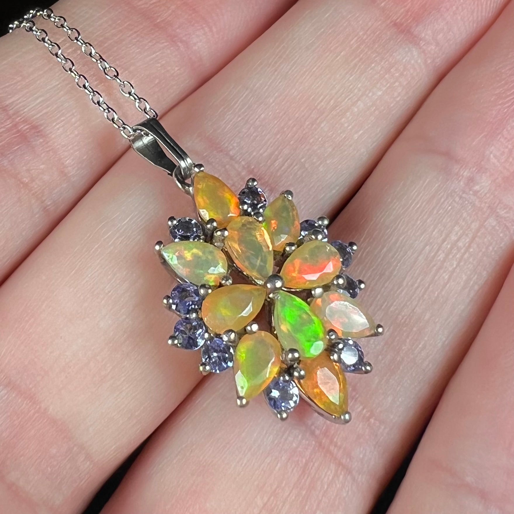 An Ethiopian fire opal pendant shown close-up in a hand, held at an ange.