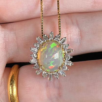 Close-up macro view of 14k gold fire opal pendant with spiked halo design set with emerald cut and round cut white sapphirs, held in hand.