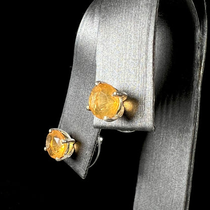 A pair of Mexican fire opal stud earrings in sterling silver shown at an angle.