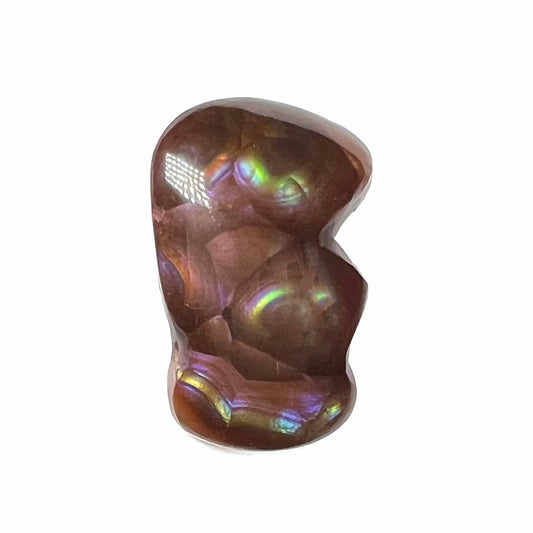 A polished, freeform shaped fire agate stone.  The stone is purple, green, and blue with red and yellow banding.