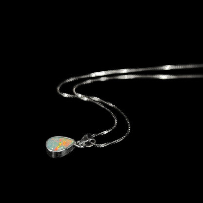 A dainty, sterling silver necklace bezel set with a natural, pear shaped opal stone.