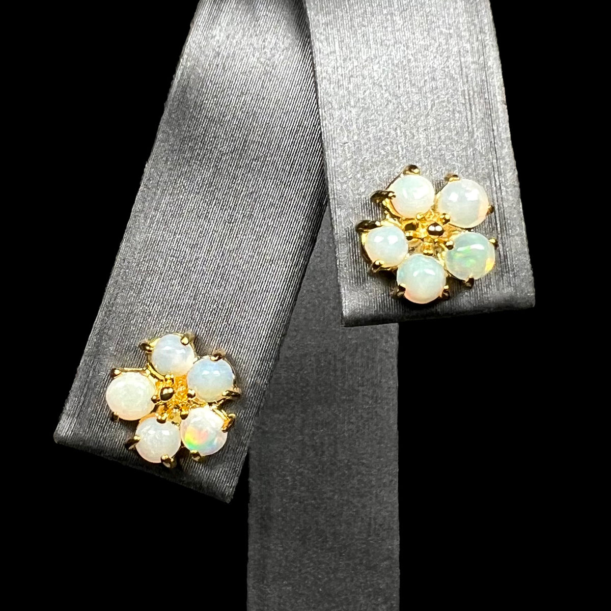 Gold-tone flower-shaped Australian opal stud earrings on earring display