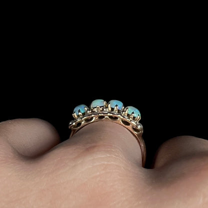 Side gallery profile view of antique four-stone prong-set opal ring, worn on finger.  One prong is missing.