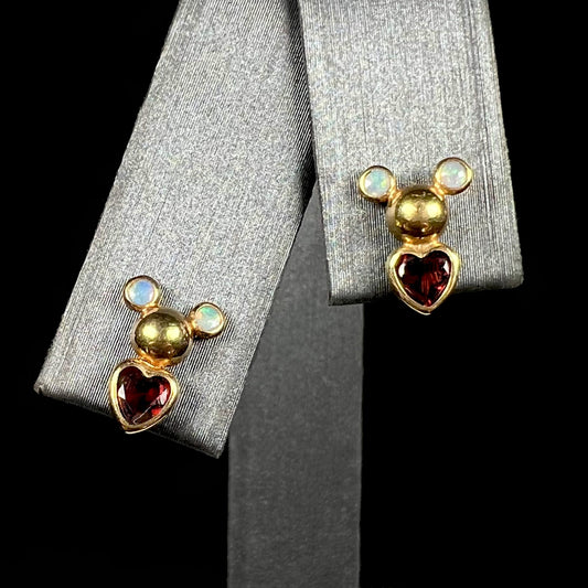 A pair of 18 karat yellow gold stud earrings set with two round fire opals and heart shaped garnets.