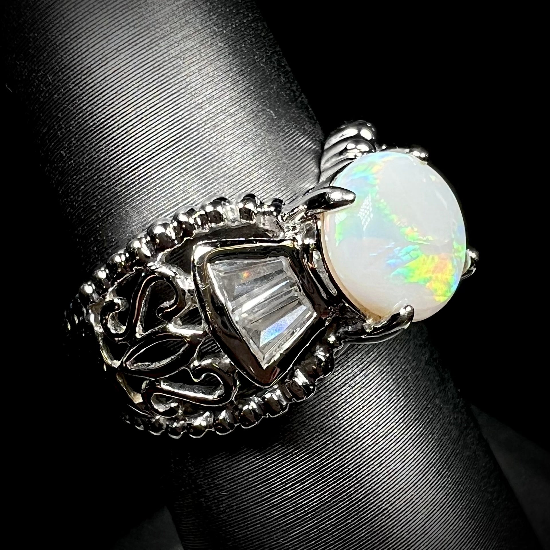 Angled view of a round Australian white opal and CZ ring in white base metal. 