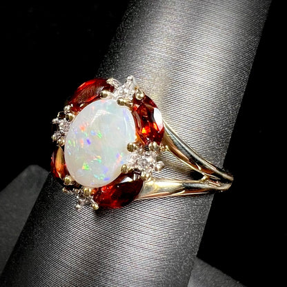 A ladies natural opal ring in yellow gold.  The opal is surrounded by red marquise cut garnets and diamonds.