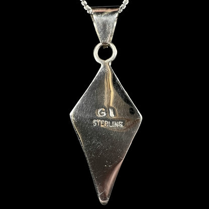 Back side of Philippines-made sterling silver pendant stamped "GI STERLING", shown against black backdrop.