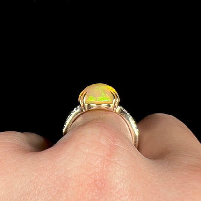 Side profile gallery view of 14k gold Ethiopian opal ring with split-prong design, shown on finger