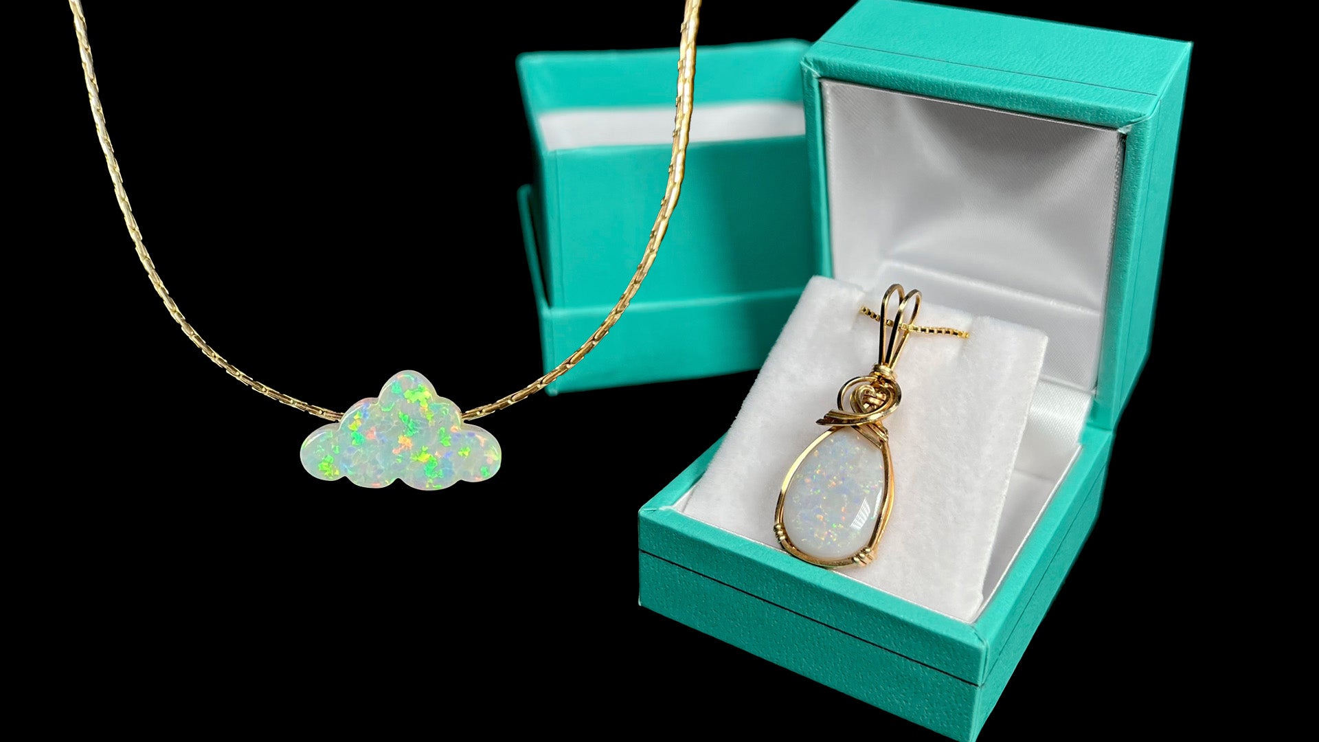 A gold-filled lab-created opal cloud necklace in front of black background next to gold-filled Australian opal pendant in blue box.