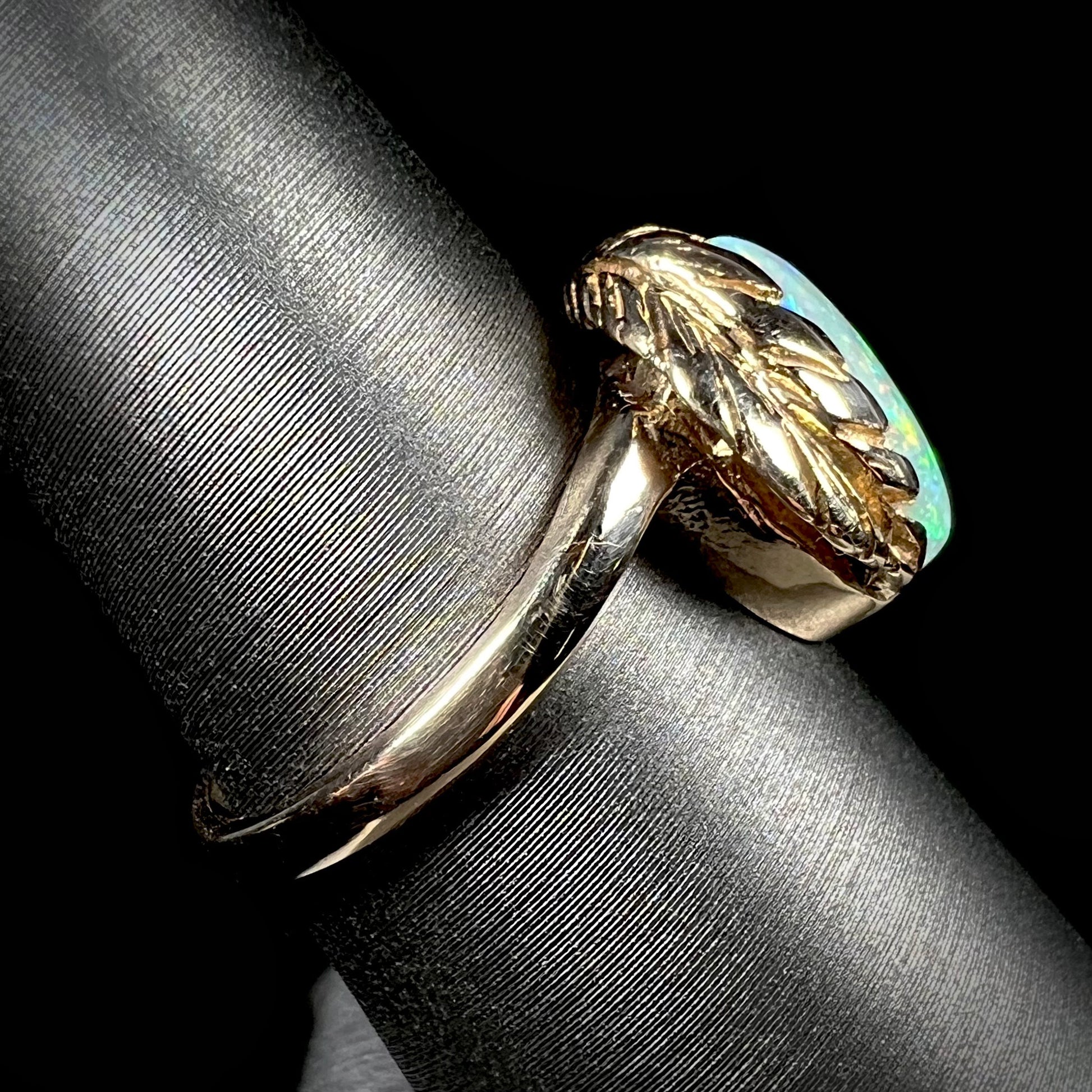 The side view of a yellow gold leaf ring mounted with a natural, Coober Pedy opal.