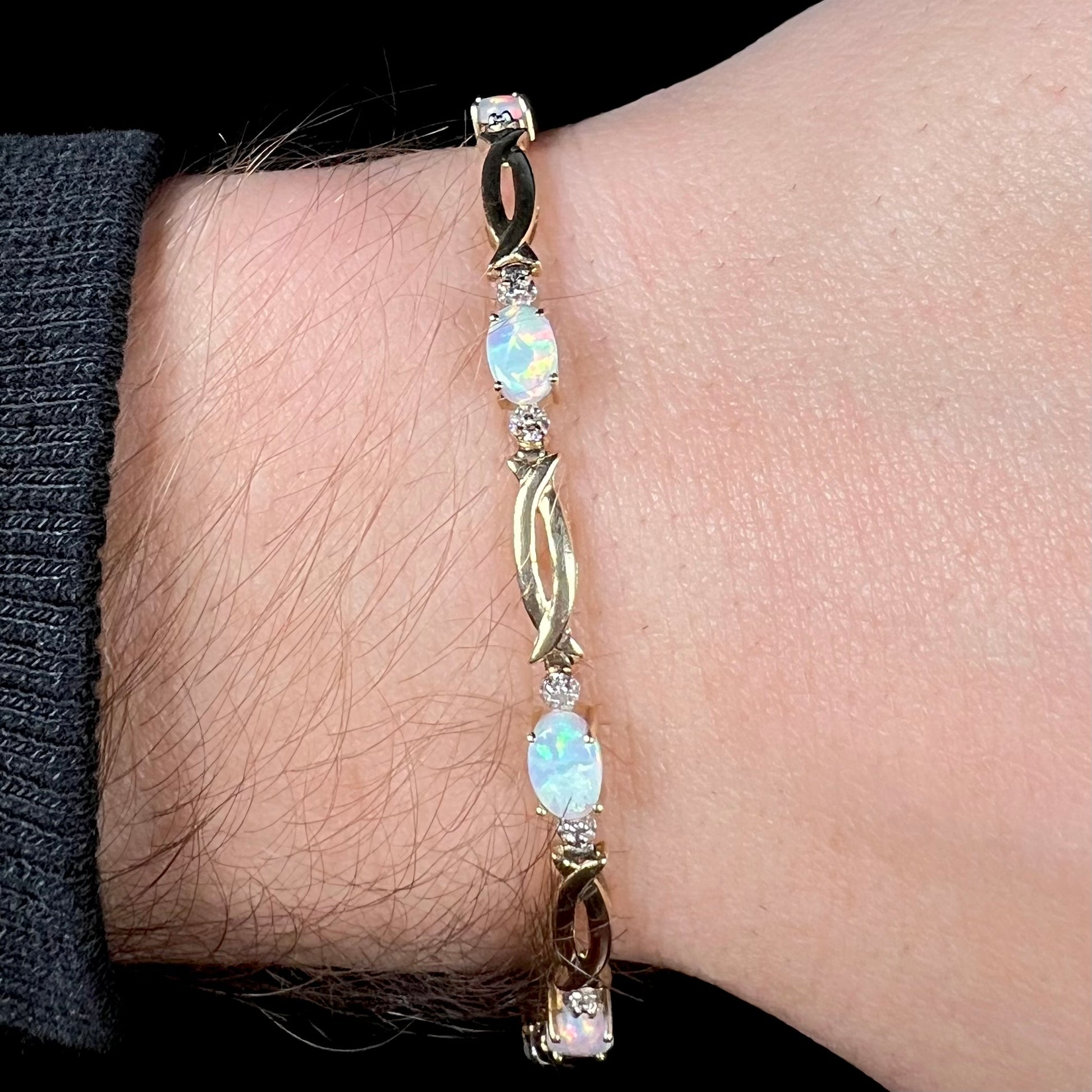 Close-up of yellow gold 1990s Modernist style synthetic opal bracelet wron around wrist.
