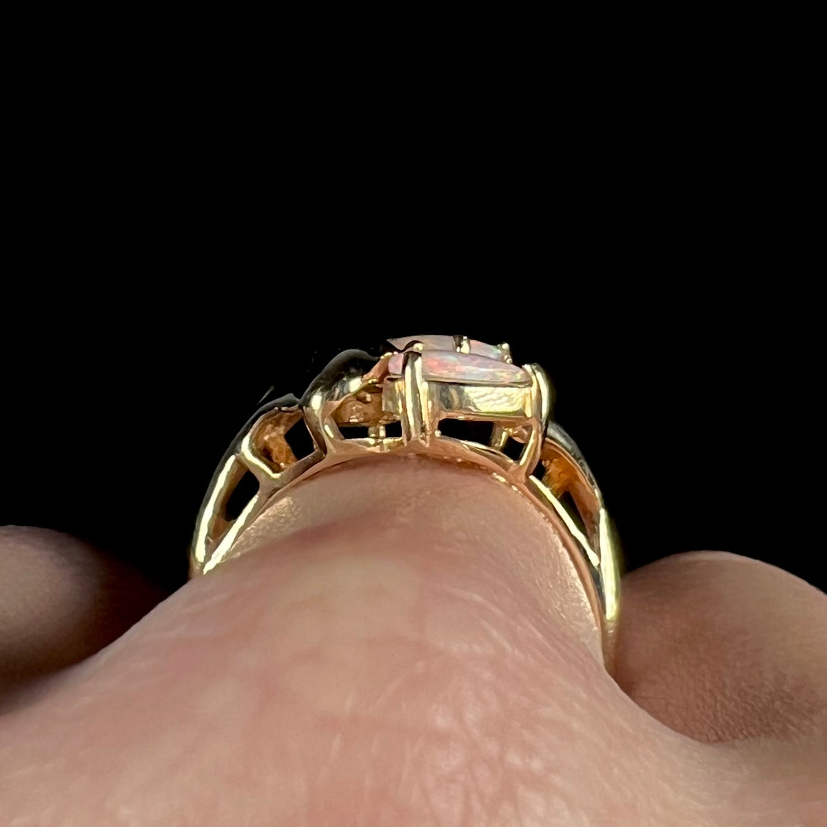 Close-up gallery view of a Modernist-style gold opal ring, worn on a finger.