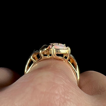 Close-up gallery view of a Modernist-style gold opal ring, worn on a finger.