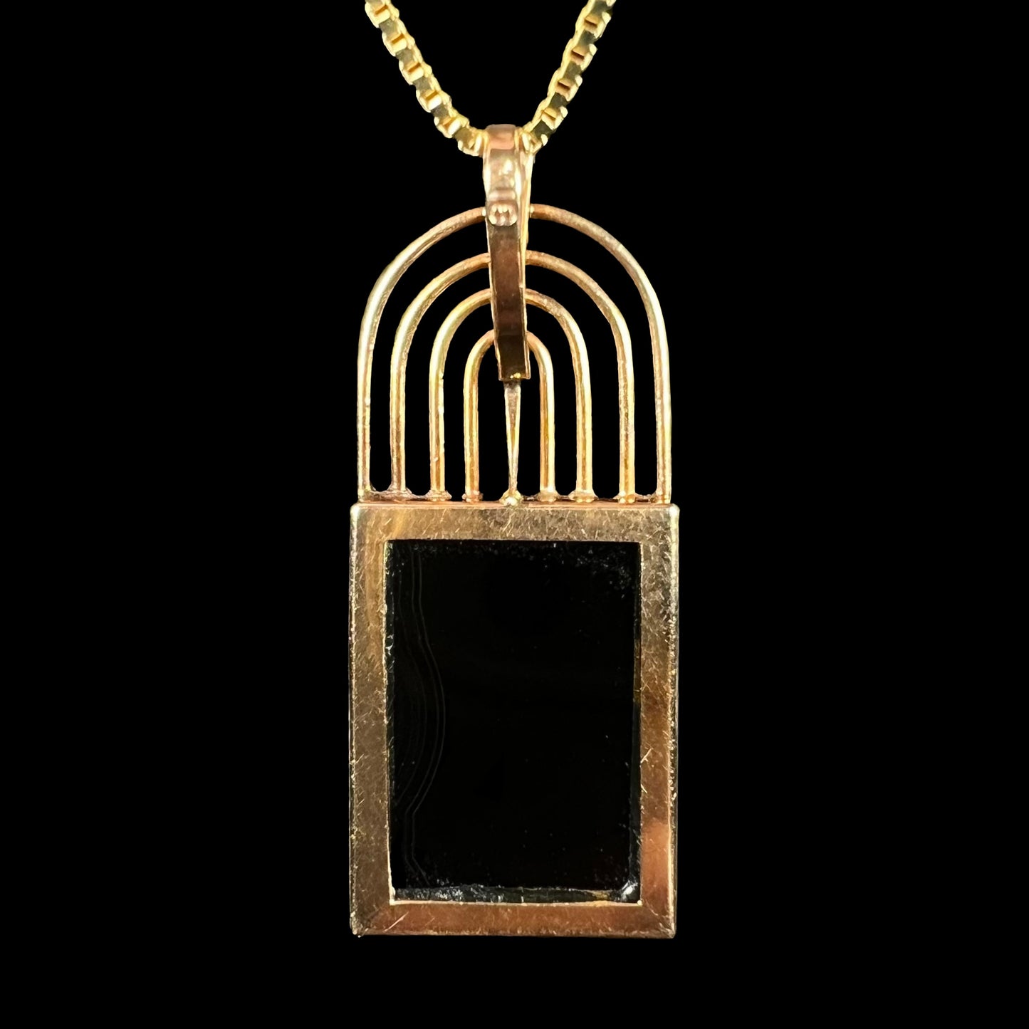 Back view of a gold mosaic opal pendant, showing the banded black onyx backing and a faintly visible ‘K18’ hallmark on the bail.