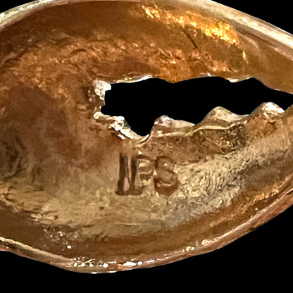 Close-up of the “IPS” hallmark on the back claw of a gold opal crab necklace, attributed to International Pearl Syndicate.