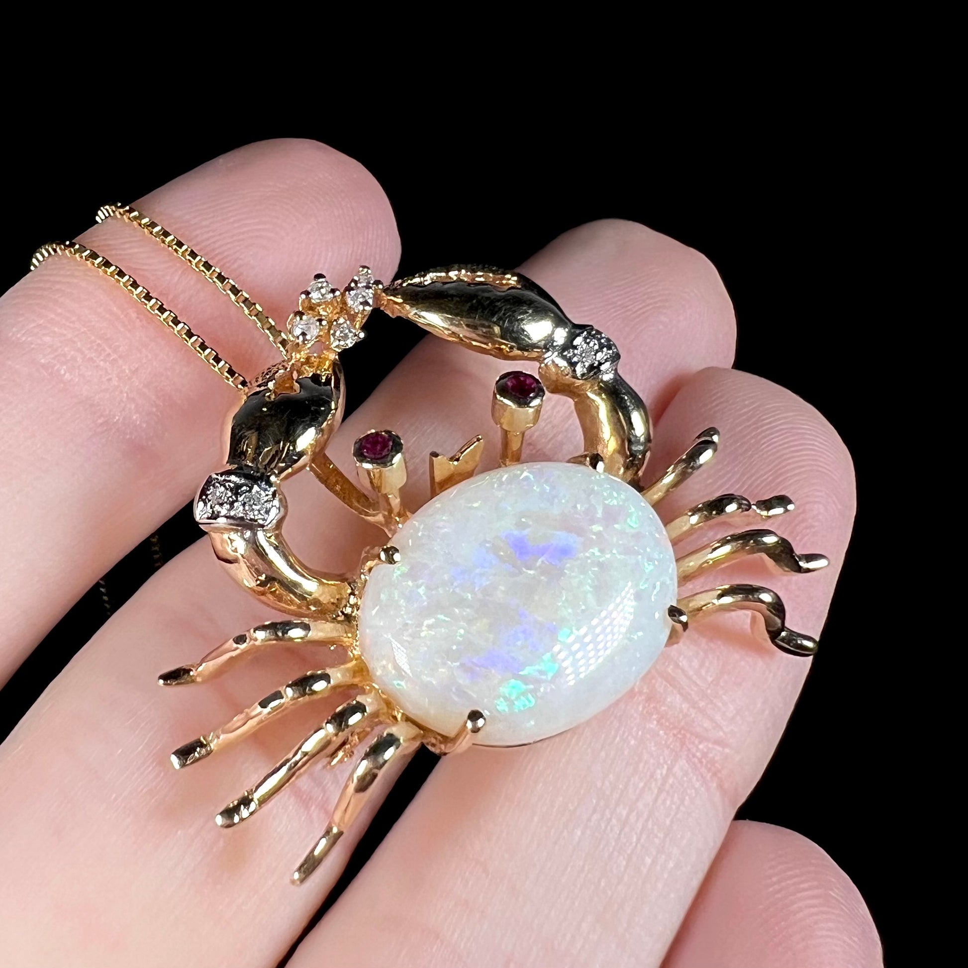 Angled macro shot of a gold opal crab necklace, showing blue and teal color play in the opal.