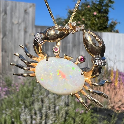 Macro view of a gold opal crab necklace in natural sunlight, showing the opal’s vibrant color play.