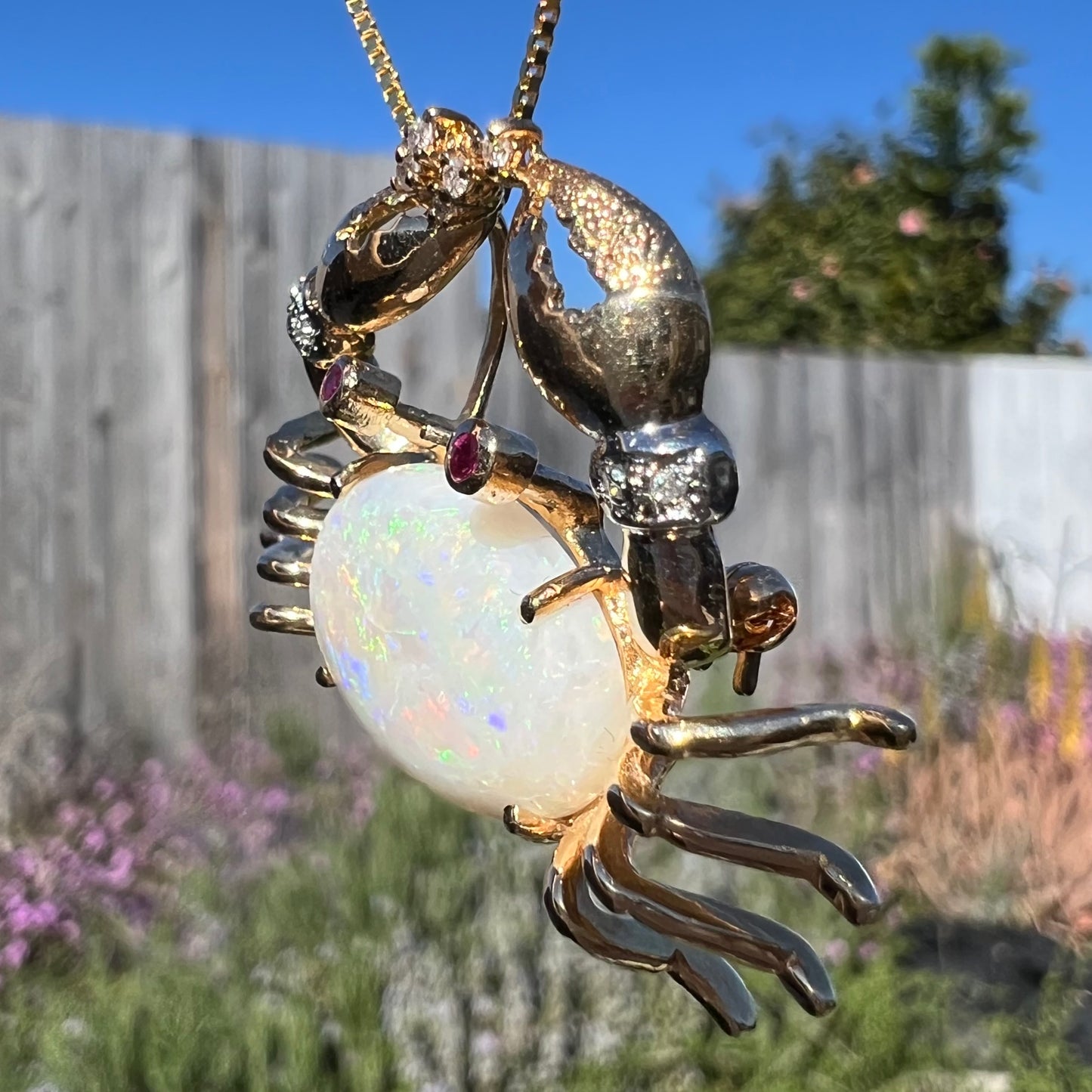 Angled macro view of a gold opal crab necklace in sunlight, with the opal appearing mostly white with no visible flashes.