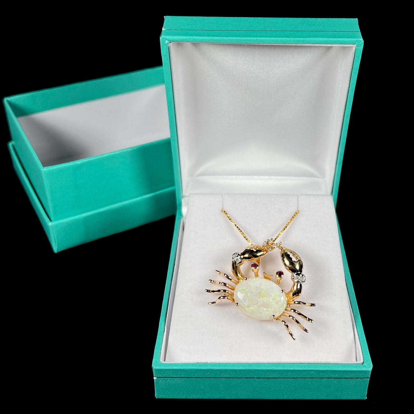 Vintage gold opal crab necklace displayed in a blue pendant box against a black background.