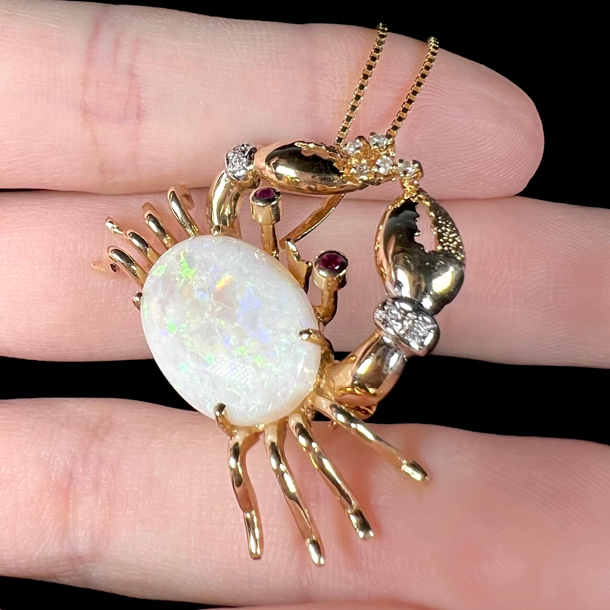 Side-angle of a gold opal crab necklace, with subtle green flashes visible in the opal.