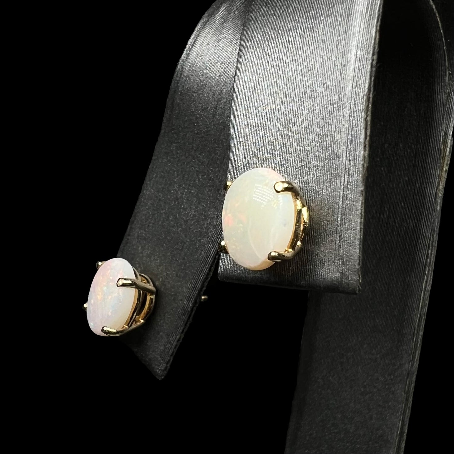 Gold opal earrings on display, angled view