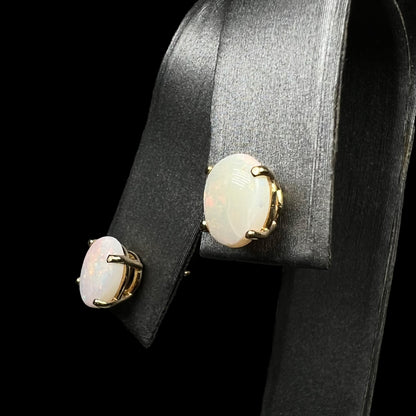 Gold opal earrings on display, angled view