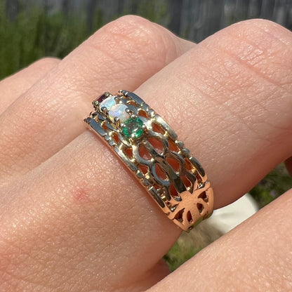 Angled sunlit view of a gold opal and emerald mother's ring.