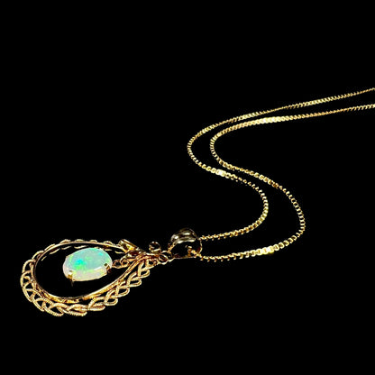 A stylistic angled shot of a gold opal filigree necklace lying on a black background, revealing a green flash.