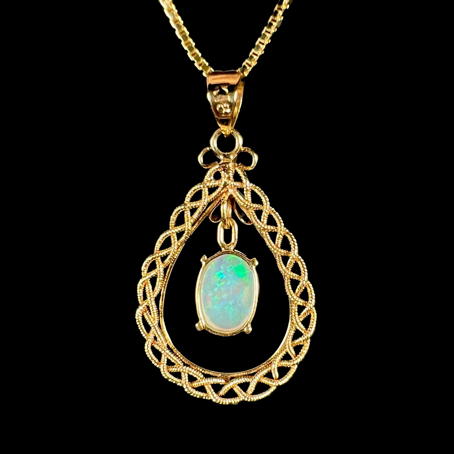 Back view of a gold opal filigree pendant, showing the open goldwork and the back of the opal.