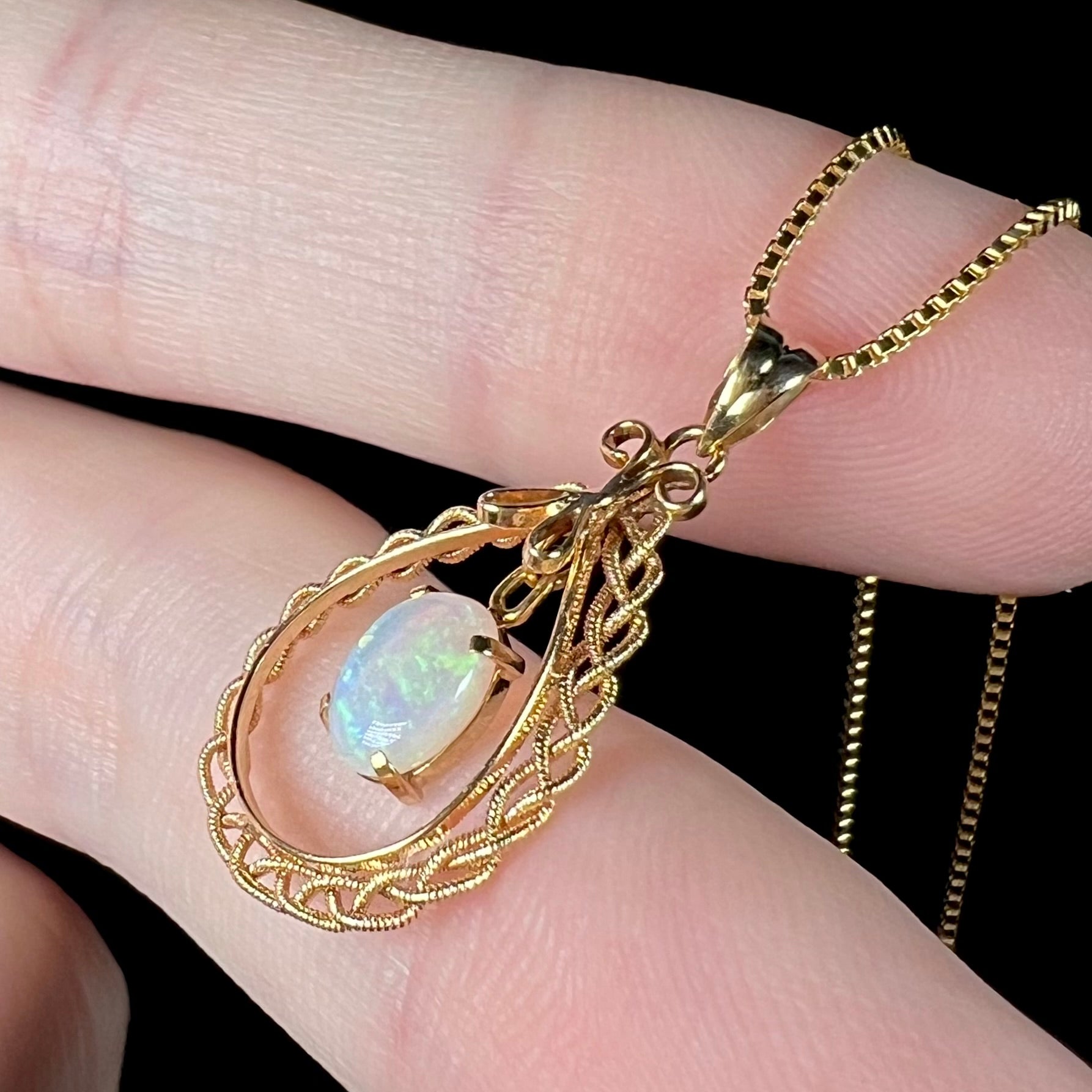 Side view of a gold opal filigree pendant, focusing on the woven filigree detailing.