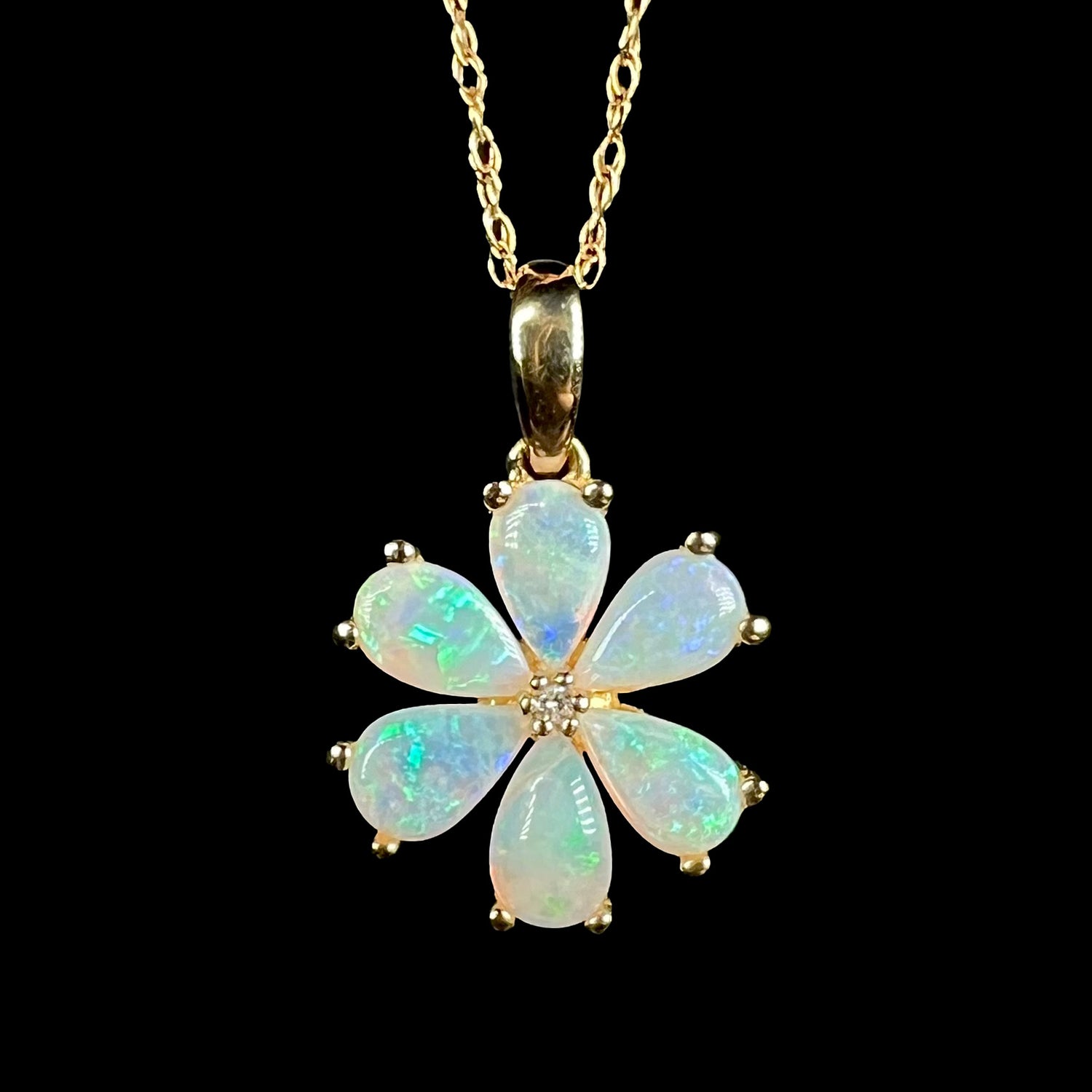 Close-up of 10k gold Australian opal and diamond flower pendant with blue flashes of color