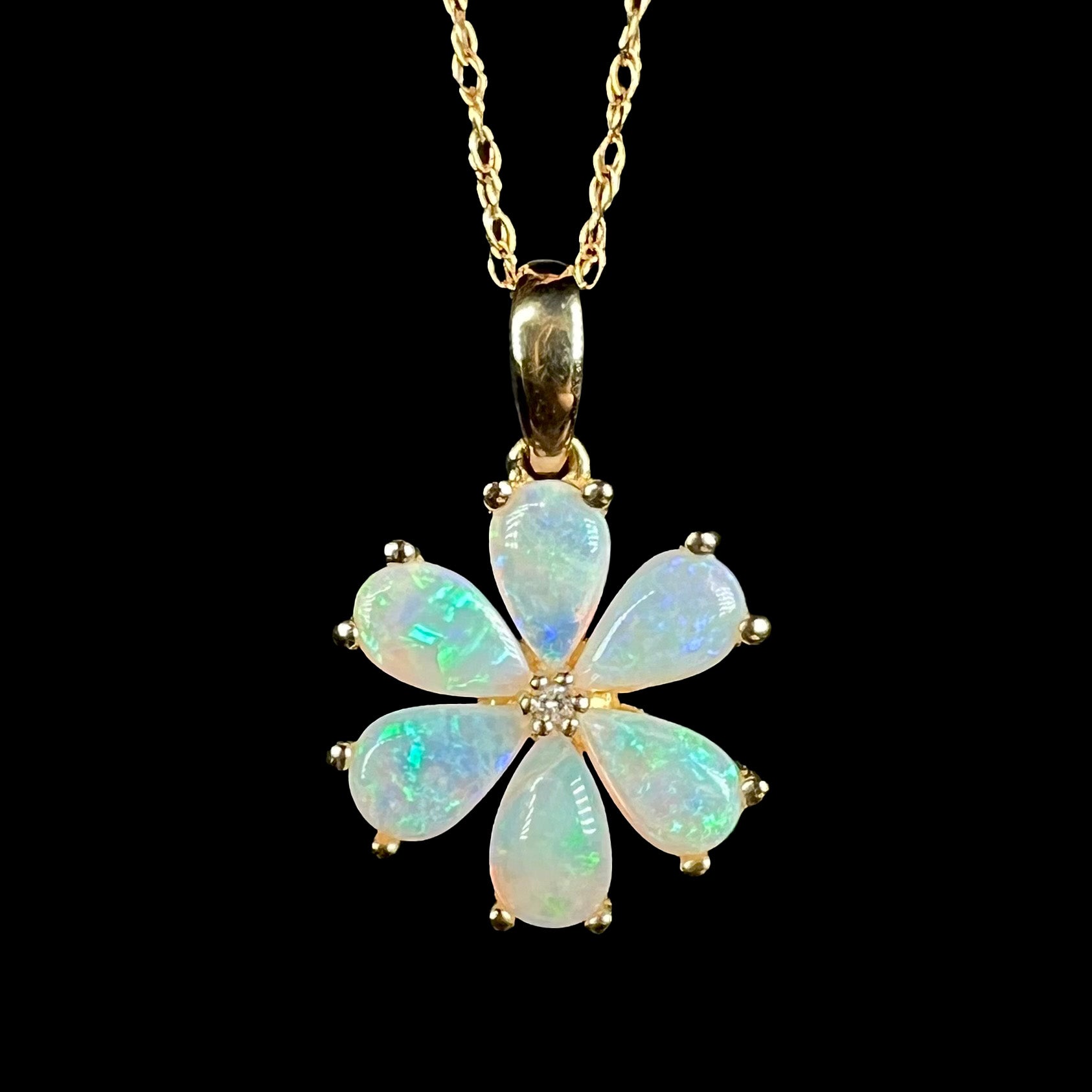 Close-up of 10k gold Australian opal and diamond flower pendant with blue flashes of color