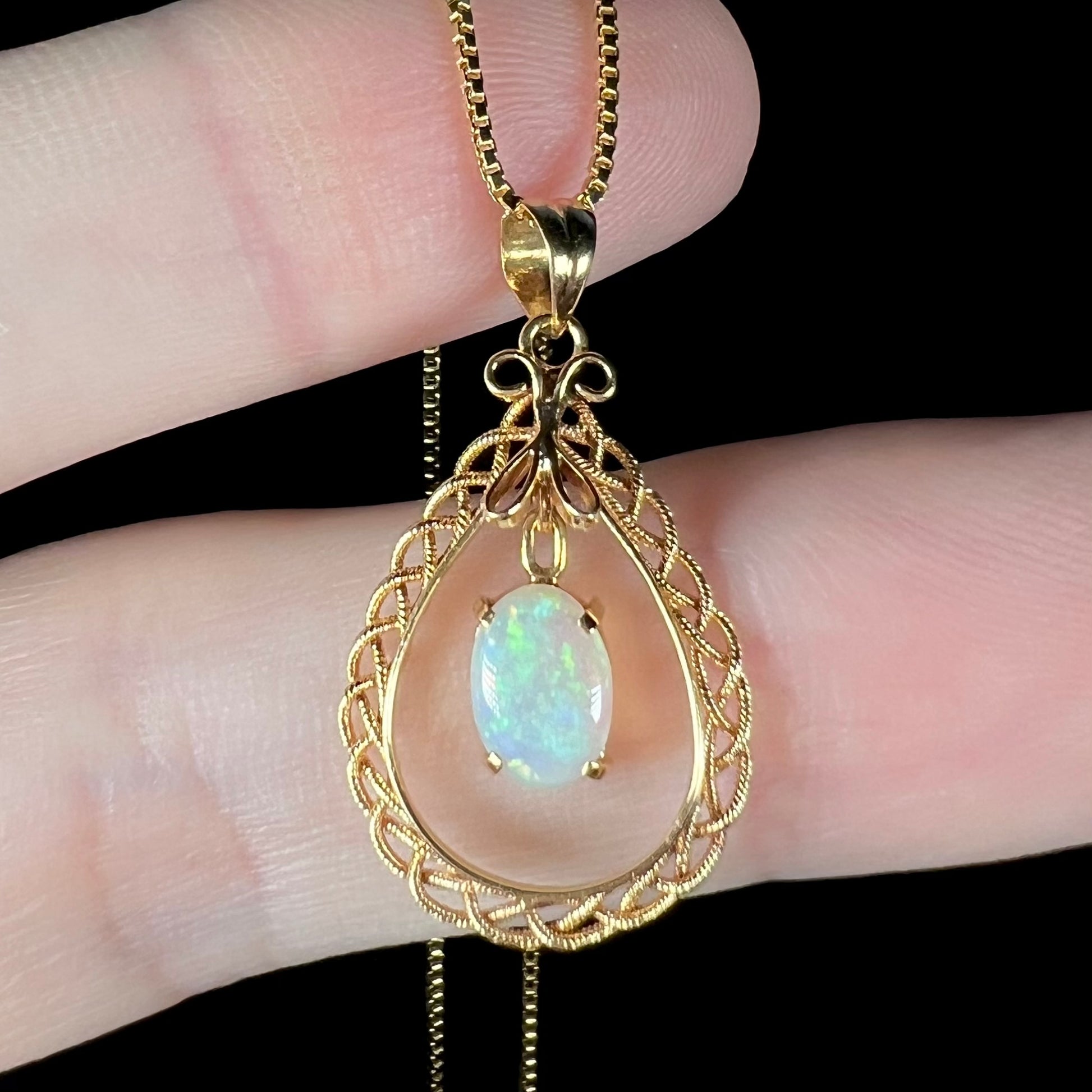 Macro view of an 18k gold opal necklace, showing a soft green glow in the opal.