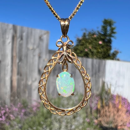 Macro shot of an 18k gold opal necklace outdoors, showing a subtle but lively green flash.