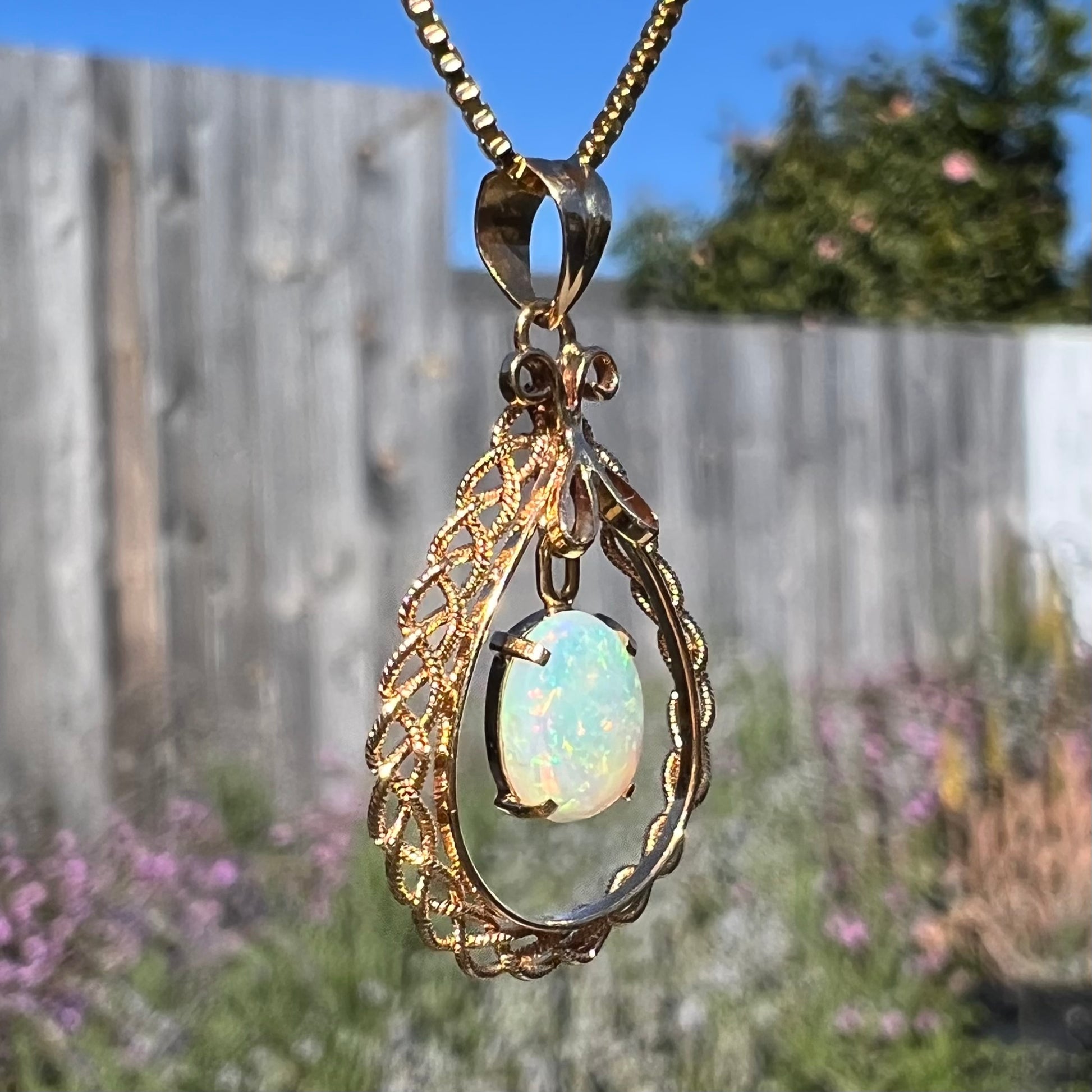 Macro shot of an 18k gold opal necklace in sunlight, with the filigree in focus and minimal opal color play.