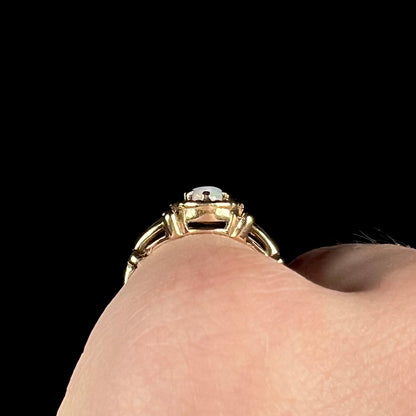 A ladies' Art Nouveau style opal solitaire ring.  The mounting is yellow gold with filigree accents.