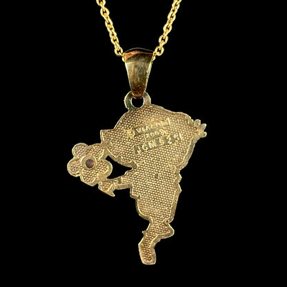 Back side of gold-plated Dora the Explorer pendant stamped "VIACOM 2009 JCM 925", shown against black background.