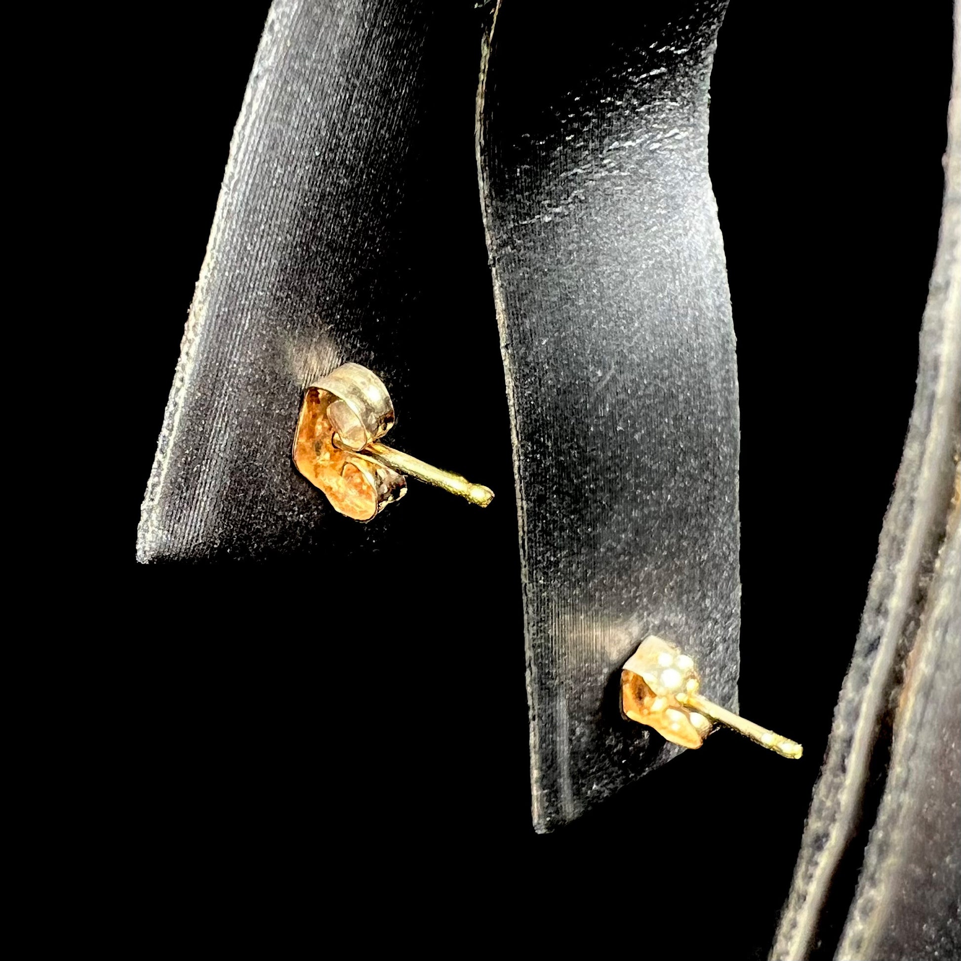 Back side of a pair of opal stud earrings, shown on a ring display focused on the earrings' posts and pushbacks.