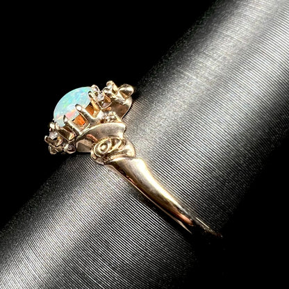 Side shank view of a yellow gold rose design opal and diamond ring, shown on ring display