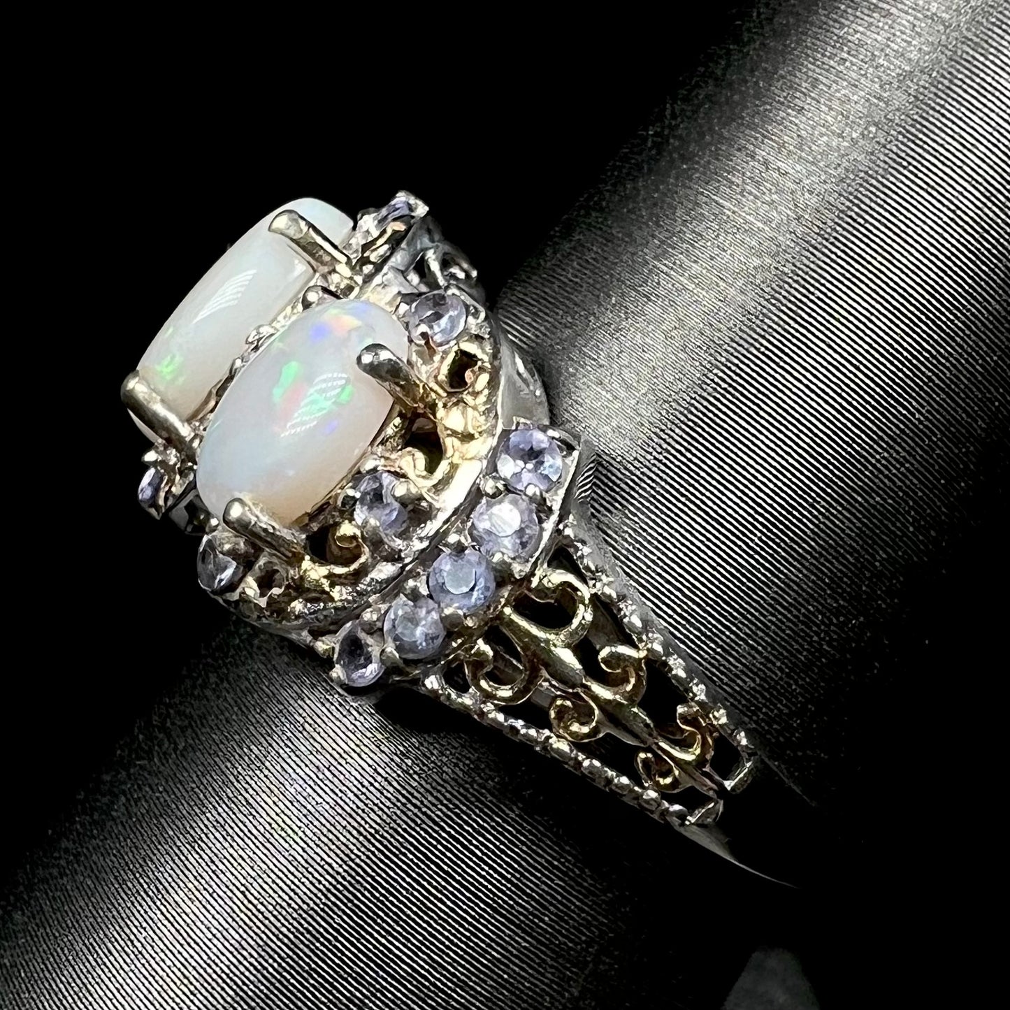 Side view of gold-tone filigree details on a sterling silver Australian opal and tanzanite ring.