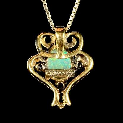 Back side of a Victorian-style gold-tone lab opal pendant.  The hallmark stamps "LA", "925", and a crown symbol are visible.