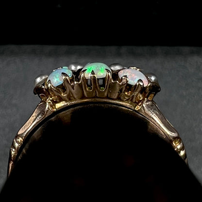 Side gallery profile view of Victorian gold ring on ring display.  Three prong-set opals are in view, as are four epoxy set pearls; the left-most pearl is lifting off of the setting