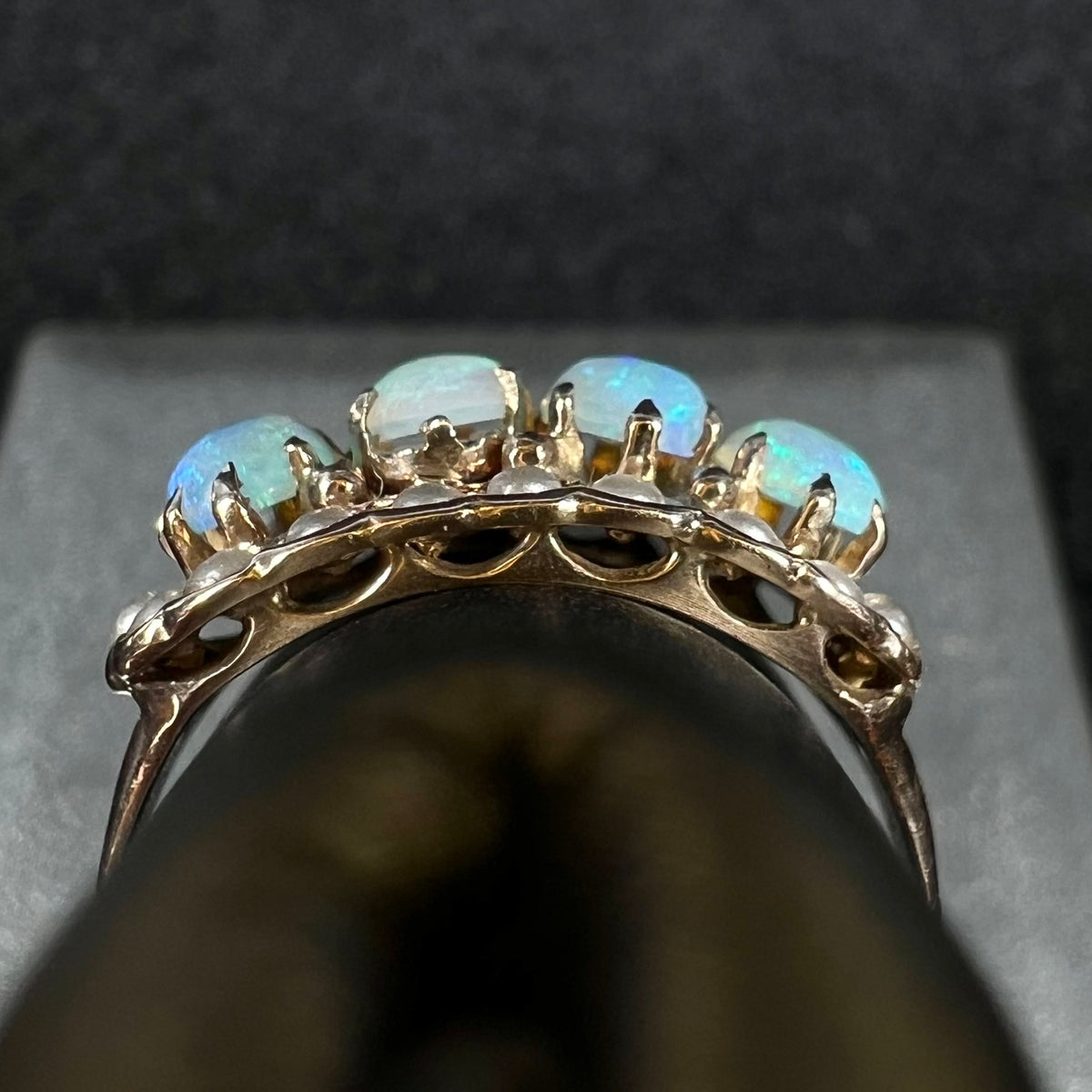Side gallery view of antique 9k gold Victorian-era opal and pearl ring, shown on ring display