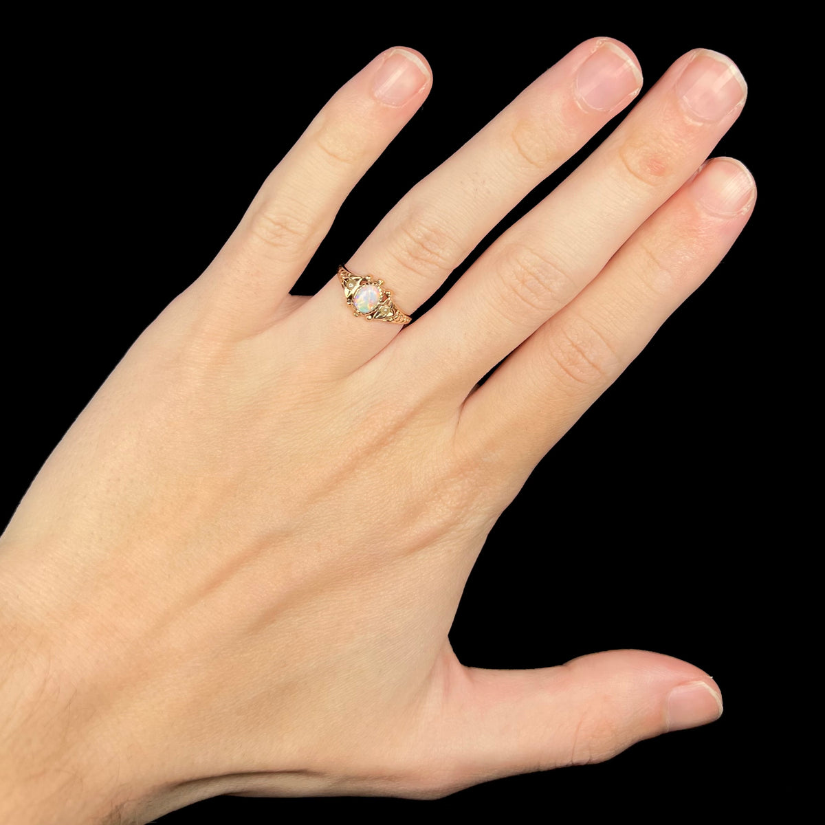Hand wearing women's antique Victorian era 9k gold opal ring under LED studio light